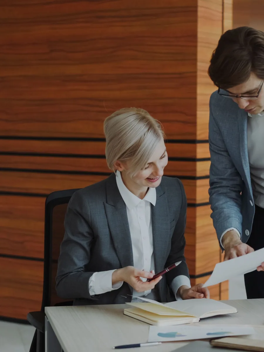 Consultant going through paperwork with a client at her desk